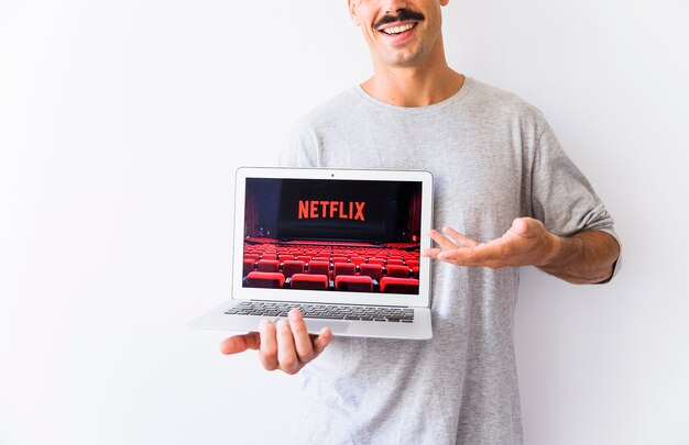 匿名の笑い男 Netflixのロゴ付きラップトップを表示 無料の写真