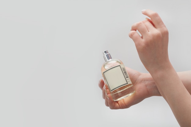 白い壁の手首に香水を塗ると 女性の手が一方の手首に他方の手で触れます 女性の香水のコンセプトです プレミアム写真