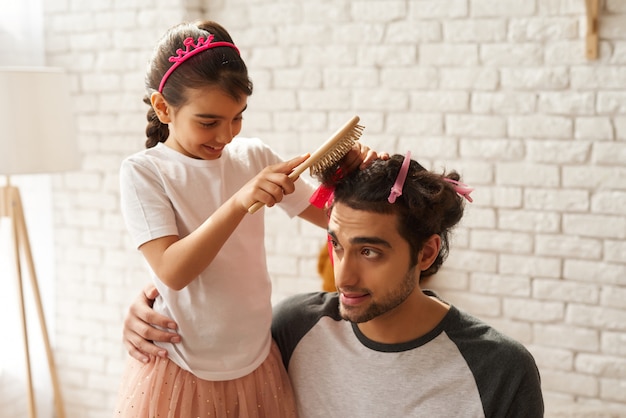 アラブ家族 女の子は新しいお父さんの髪型を作っています プレミアム写真