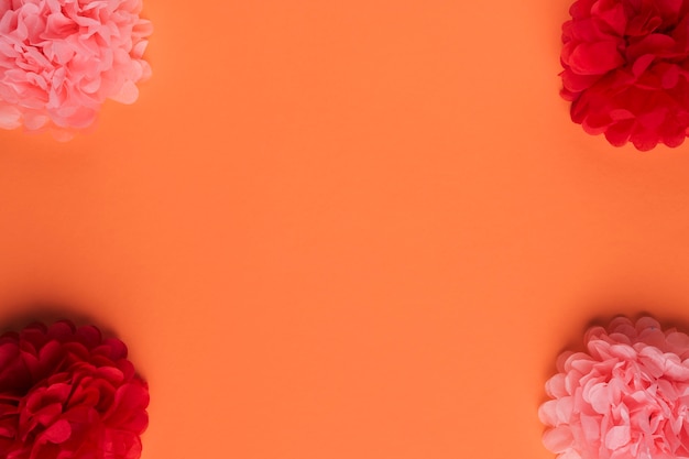 オレンジ色の表面上の美しい折り紙の紙の花の配置 無料の写真