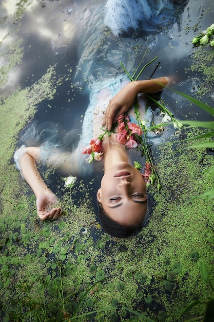 Premium Photo | Art beautiful romantic woman lies in swamp in blue long ...