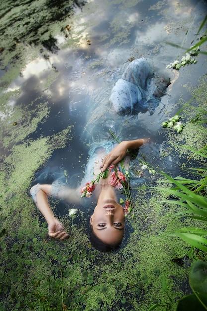 Premium Photo | Art beautiful romantic woman lies in swamp in blue long ...