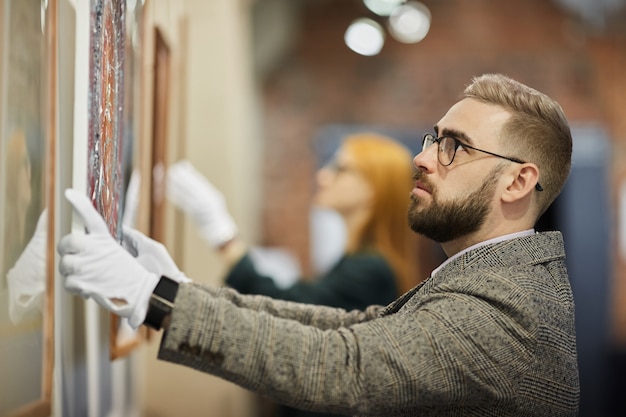 Premium Photo | Art manager hanging the painting