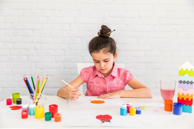 Artist Kid Painting On White Paper Over The Desk Against White