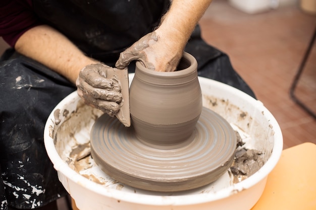 Premium Photo | Artist makes clay pottery on a spin wheel