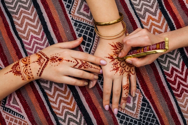 Artist making mehndi on womans hand on bright table Free Photo