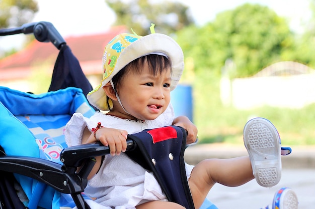 Premium Photo | Asian baby child girl sitting in a stroller. playful kid.