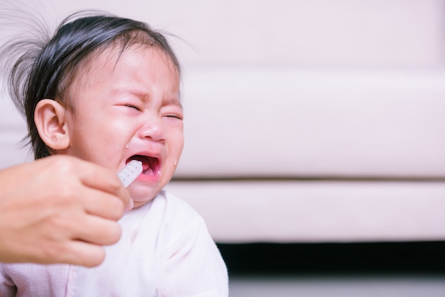 Asian baby sick but refuses eating medicine by syringe with copyspace Premium Photo