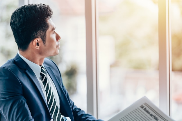 Asian businessman sitting reading newspaper in office smile on face Premium Photo