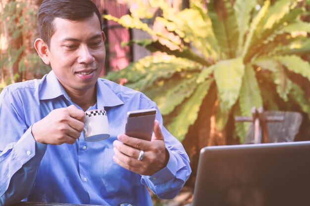 Asian businessman smiles while receiving a text message from the smartphone Premium Photo