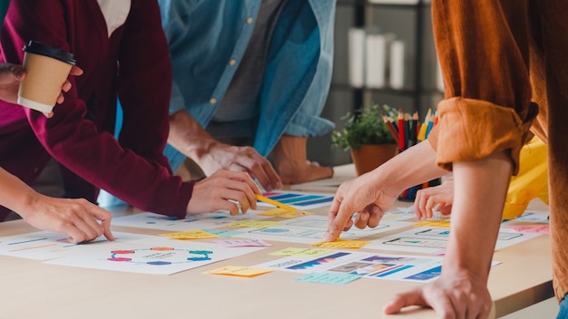 Asian businessmen and businesswomen meeting brainstorming ideas about creative web design planning application and developing template layout for mobile phone project working together in small office. Free Photo