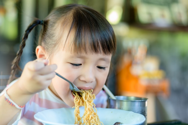 自宅でインスタントラーメンを食べるアジアの子供女の子 プレミアム写真