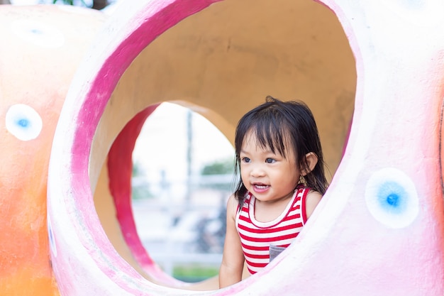 笑って笑っているアジアの子供の女の子 彼女は公園の遊び場でおもちゃで遊んでいます プレミアム写真