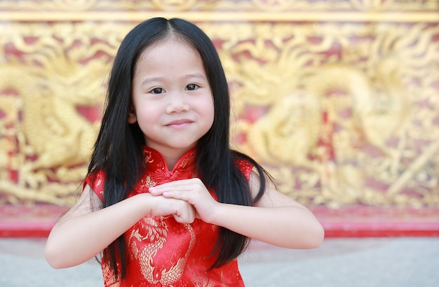 Asian child girl wearing red cheongsam with greeting gesture celebration Premium Photo