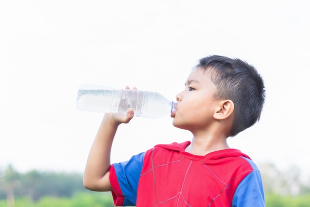 ペットボトルで水を飲むアジアの子供学生少年 プレミアム写真