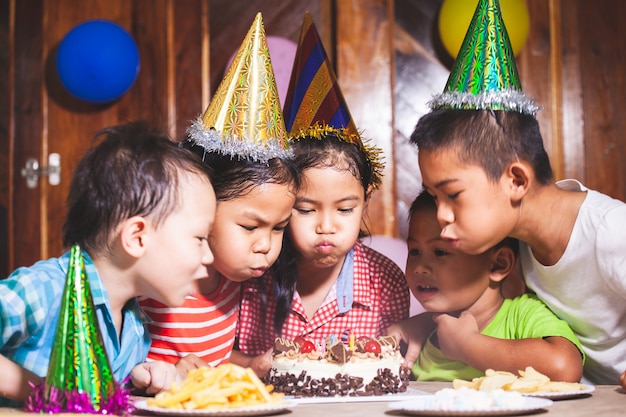 アジアの子供たちの女の子と男の子が一緒にパーティーで誕生日を祝い 誕生日ケーキにろうそくを吹き プレミアム写真