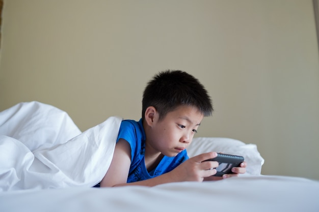 Premium Photo | Asian chinese kid playing on smartphone in bed