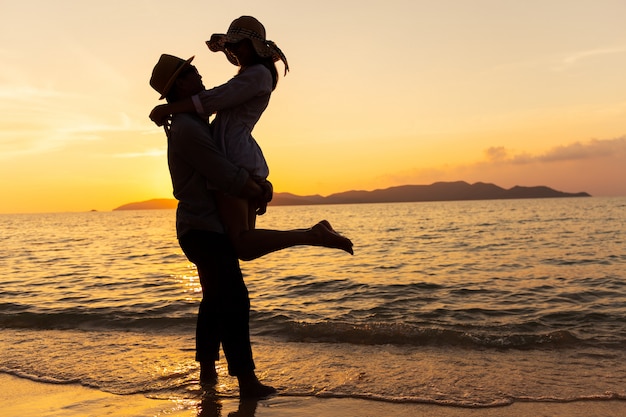 ビーチに立っている間彼らの気持ちを表現するアジアカップル 日没で海で抱っこする若いカップル プレミアム写真