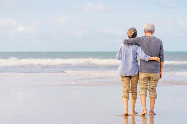 Asian couple senior walking on the beach holding hands.honeymoon family together happiness lifestyle.life after retirement.plan life insurance Premium Photo