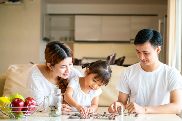 Premium Photo | Asian family teach asian cute girl saving money putting ...