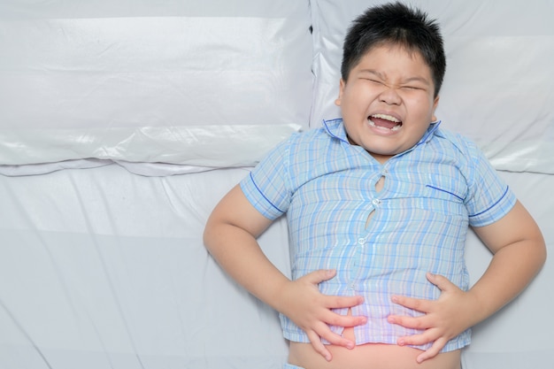 プレミアム写真 腹痛を患っているアジア太った子供