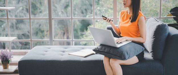 Premium Photo | Asian female sitting on couch using smartphone and ...