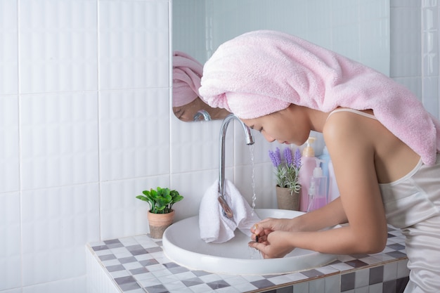 Asian girl washes face. Free Photo