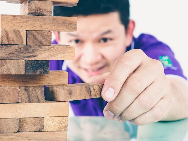 Asian guy is playing a wood blocks tower game for practicing physical and mental skill Free Photo