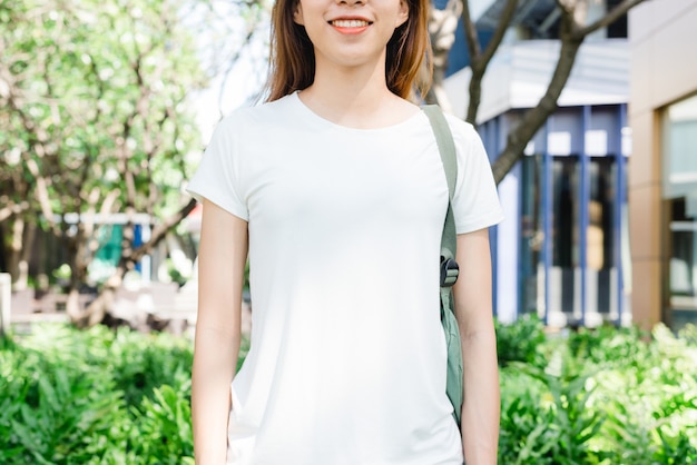 アジアのヒップスターの女の子長い白いブランクのtシャツの長い茶色の髪が通りの真ん中に立っています 女性 無料の写真