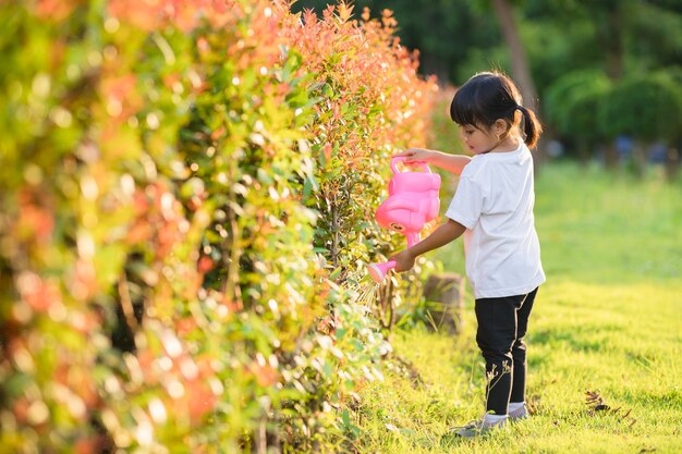 Premium Photo | Asian little child girl pouring water on the trees. kid ...