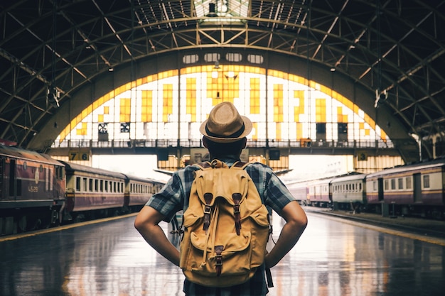 Asian man backpacking starting traveling on train station, journey on holiday concept . Premium Photo