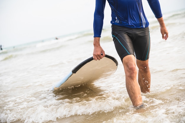 Asian man carry surfboard at the beach Premium Photo