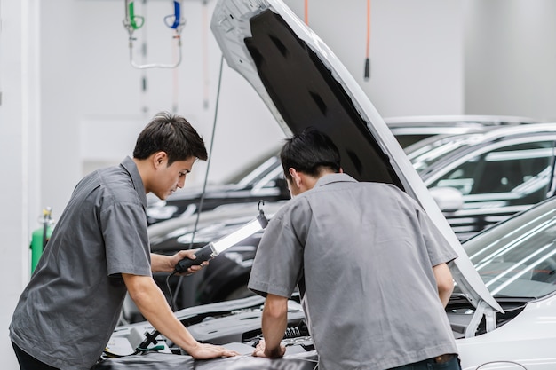 Asian mechanics open the car hood and checking the engine at maintainance service center Premium Photo