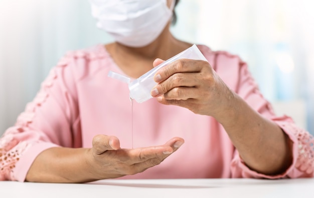 Premium Photo | Asian senior woman wear surgical mask in pink shirt pouring  hand sanitizer portable gel on her palms and hands for prevent and  protection coronavirus or covid-19.
