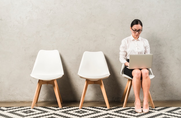 Asian Serious Young Businesswoman Sitting On Chair Typing Over The