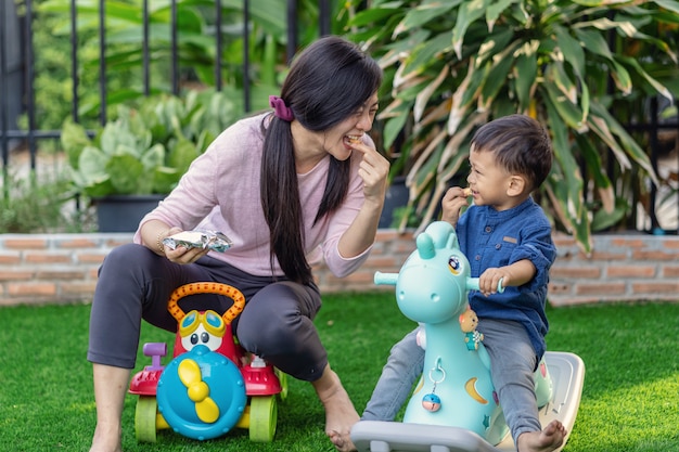 Asian single mom with son are playing with toy and eating together ...
