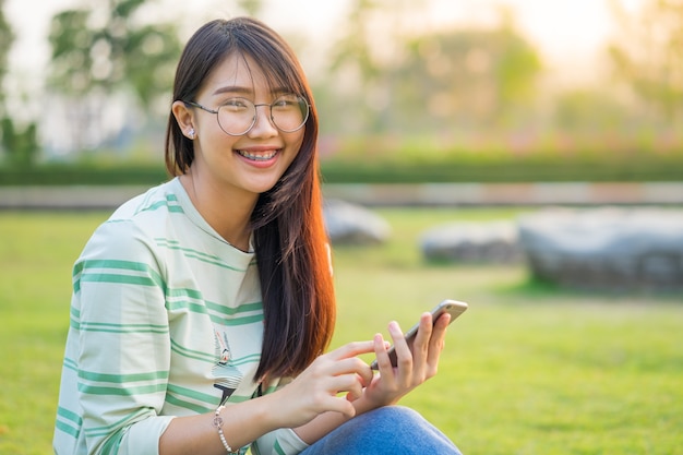 Asian Teen Girl Using Smartphone In The Lawn She Is Wearing Braces And