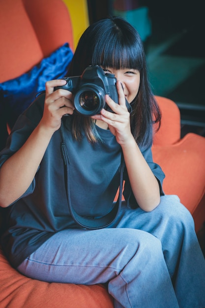ソファに座って デジタル一眼レフカメラで写真を撮るアジアのティーンエイジャー プレミアム写真