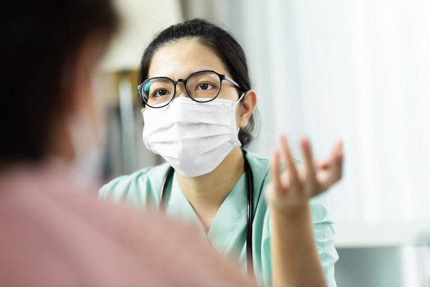 Premium Photo | Asian woman doctor in green uniform wear eyeglasses and  surgical mask talking, consulting and giving advice to elderly female  patient at the hospital.