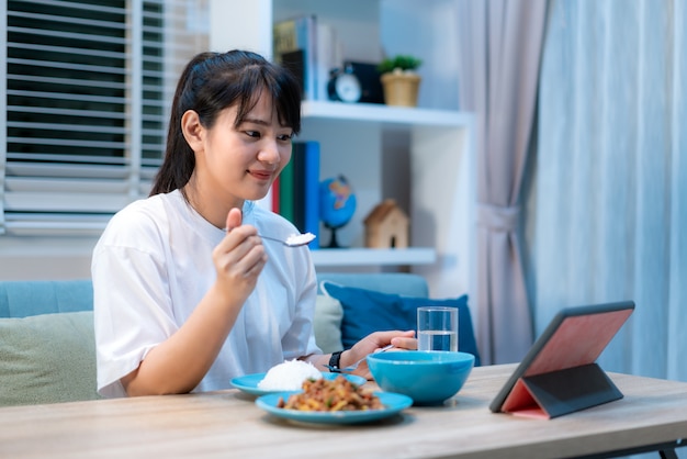 Premium Photo | Asian woman eating food in front of the laptop while having  an online call