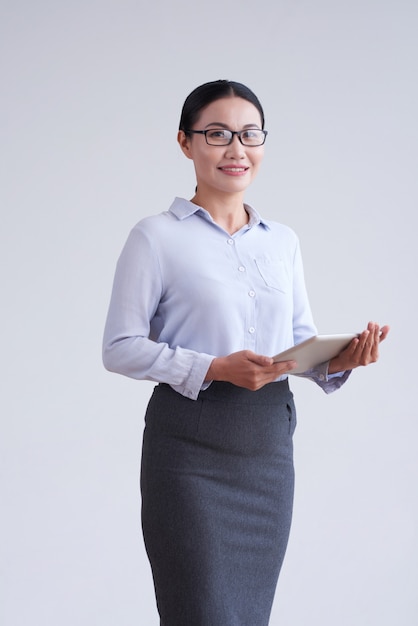 Free Photo Asian Woman In Glasses Smart Blouse And Skirt Posing In Studio With Tablet