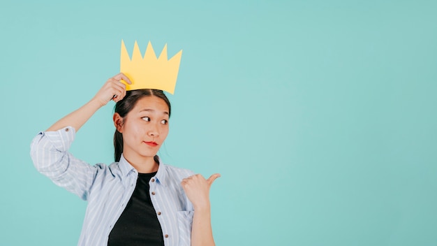 Asian woman in paper crown pointing right | Free Photo