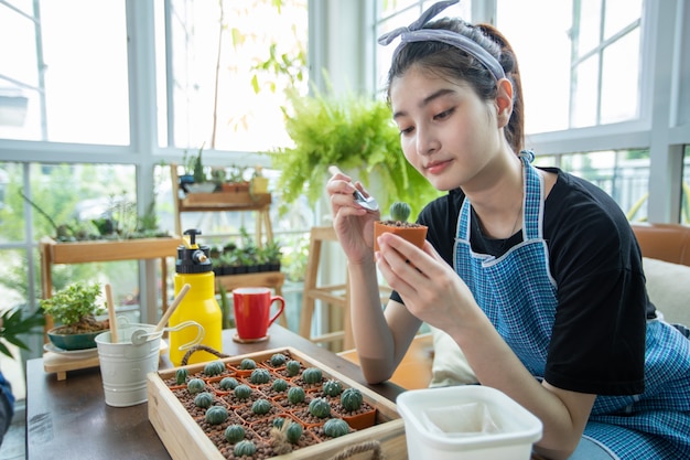 アジアの女性の植栽と庭師自宅の庭の植物に水を噴霧します プレミアム写真