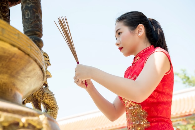 Asian woman praying with incense sticks during chinese new year Premium Photo