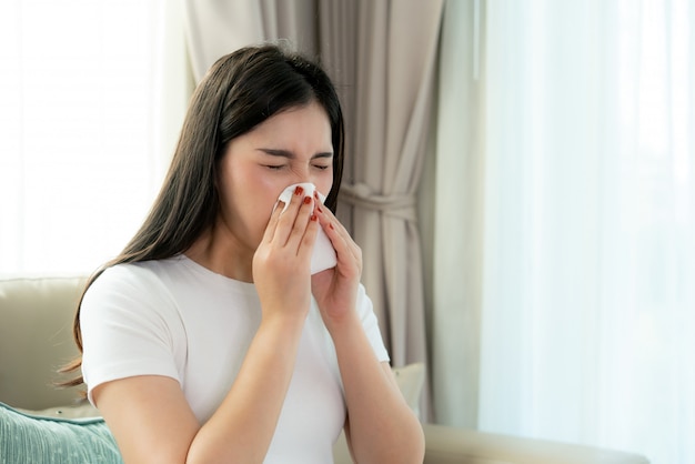 アジアの女性の鼻にくしゃみとティッシュペーパーに冷たい咳で病気と悲しい プレミアム写真