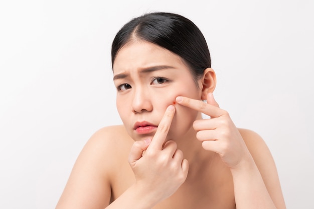 Asian woman squeezing pimples on her face, skin care lifestyle concept. Premium Photo