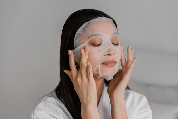 Asian woman using a sheet mask Free Photo