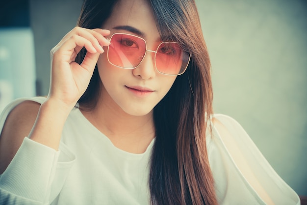 Asian woman wear sunglasses and sitting in a coffee shop. Premium Photo