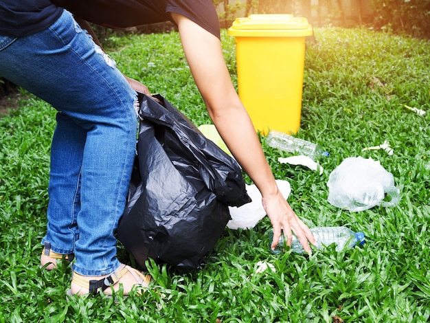 Premium Photo | Asian women collect garbage in black bags with yellow ...