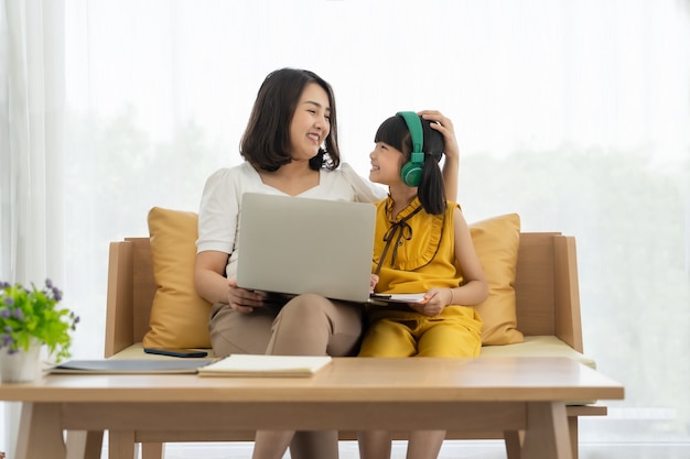Premium Photo | Asian young mother with laptop teaching kid to learn or study online at home